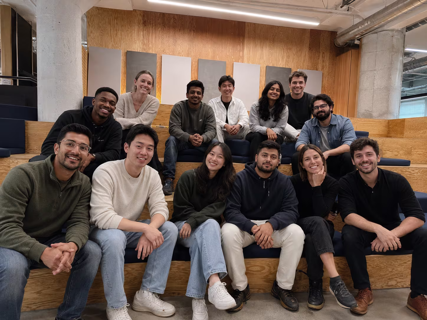 The Chatref team gathered together on wooden bleacher steps in a modern office
